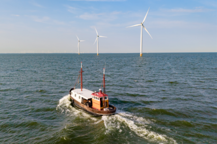 Windmill park in espel, netherlands, with a boat among renewable energy turbines